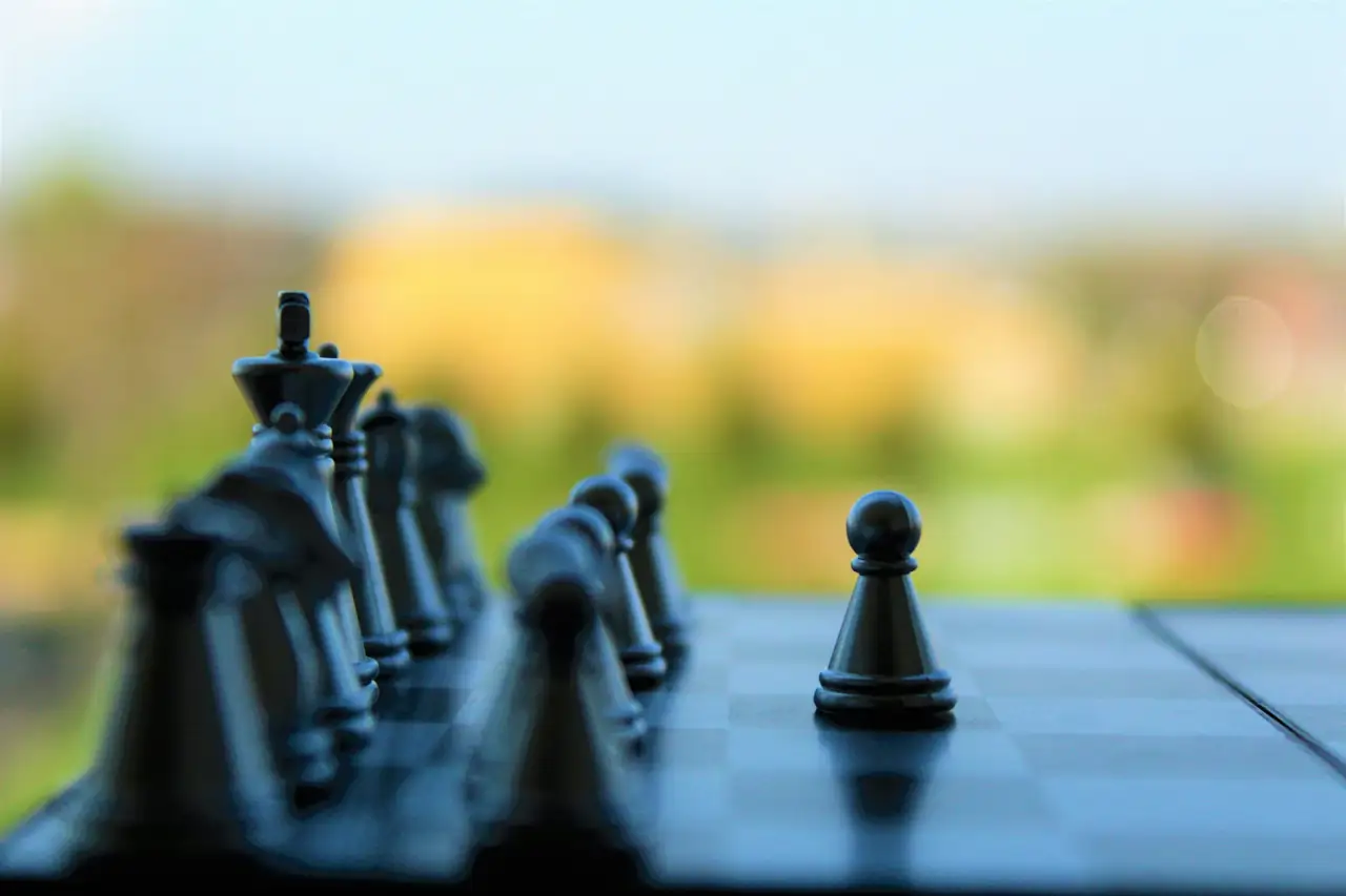 Pièces d’échecs alignées sur un échiquier, un pion avancé devant les autres