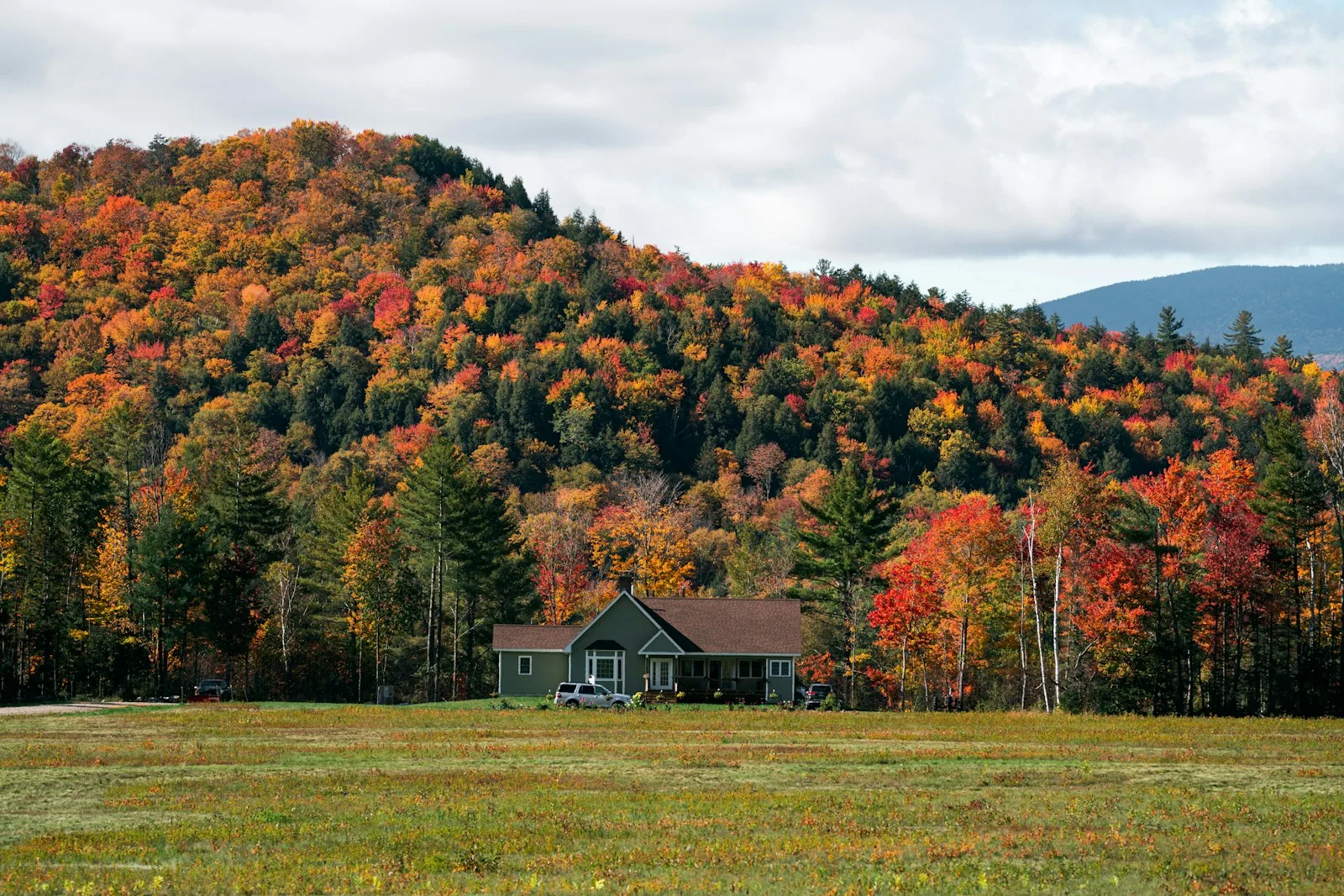 Maison au pied d’une colline boisée aux couleurs d’automne